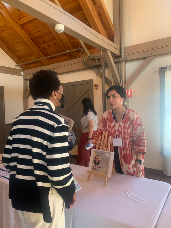 Naheed Asar talks to a woman at a table